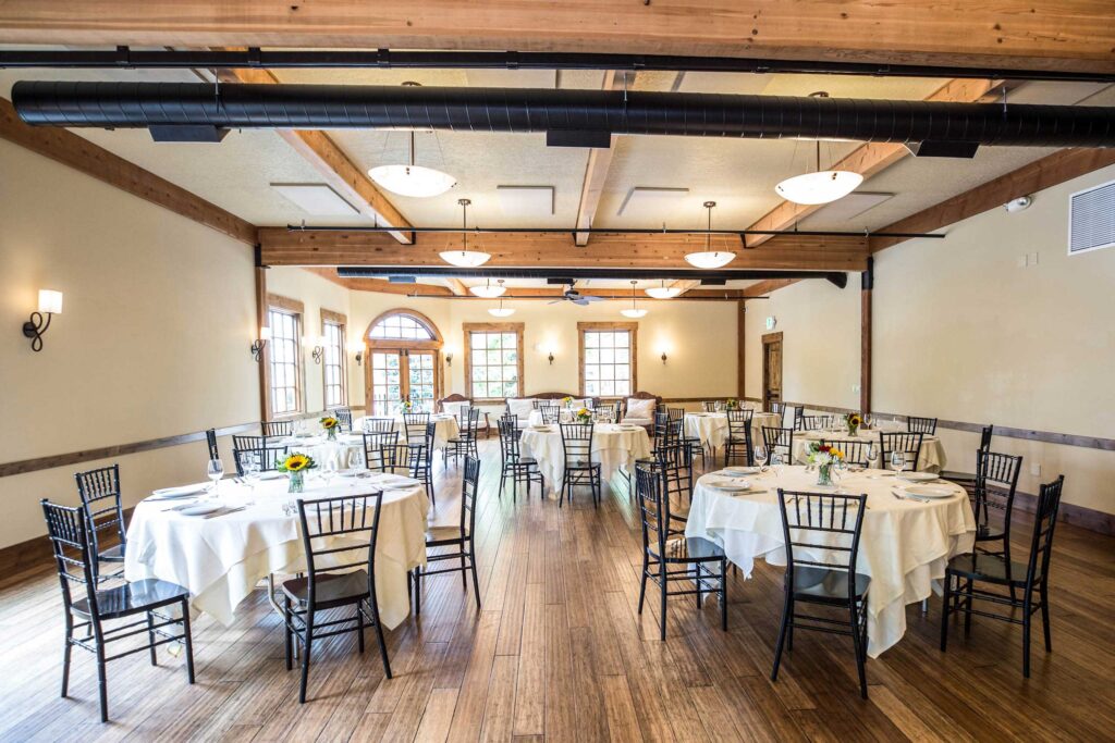 Elephants Delicatessen Corbett room set up for dining with tables, chairs, white table cloths, and table settings with flowers