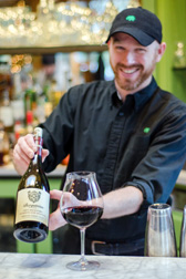 a sommeliar offering red wine with a bottle and glass
