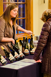 a wine table with multiple bottles and two women looking at the wine list