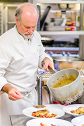chef serving food on plates from pot