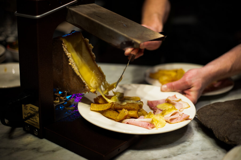 raclette cheese pouring over hand and golden potatoes