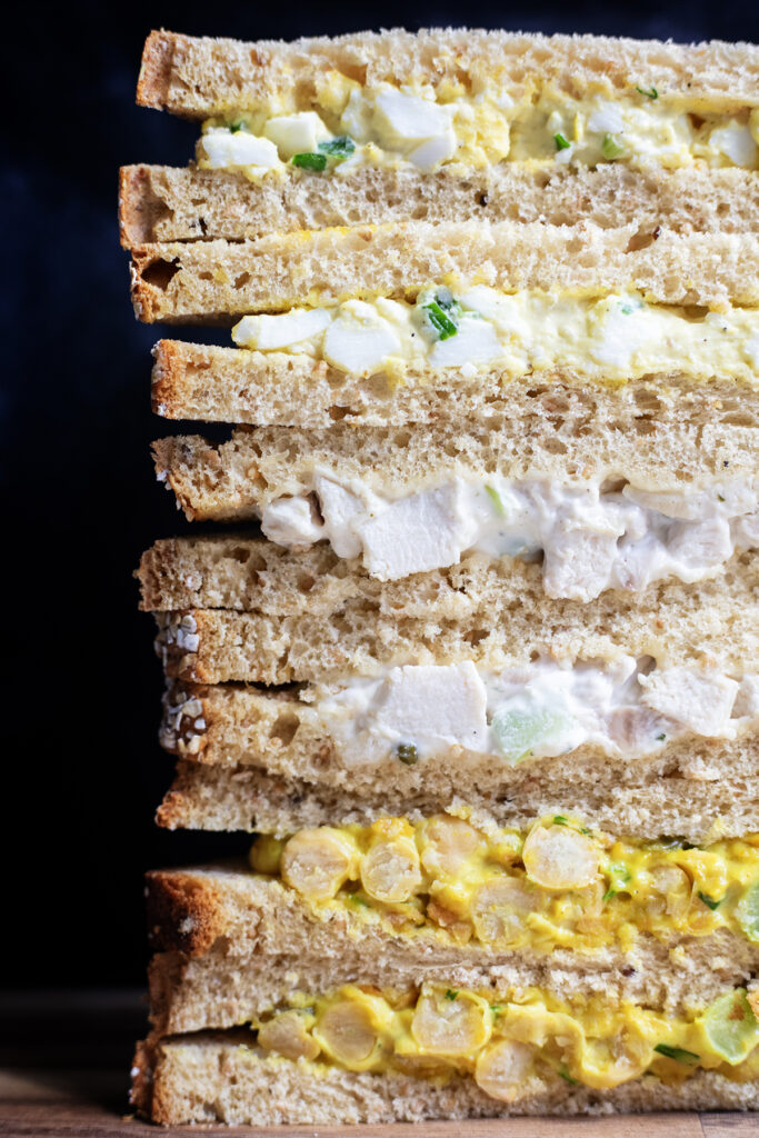 stack of curried chickpea, chicken salad, and egg salad sandwiches